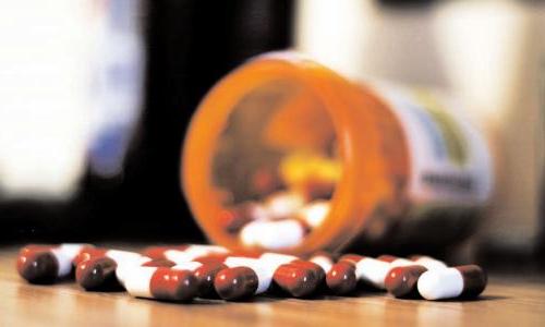 Pill bottle with pills spilled on table